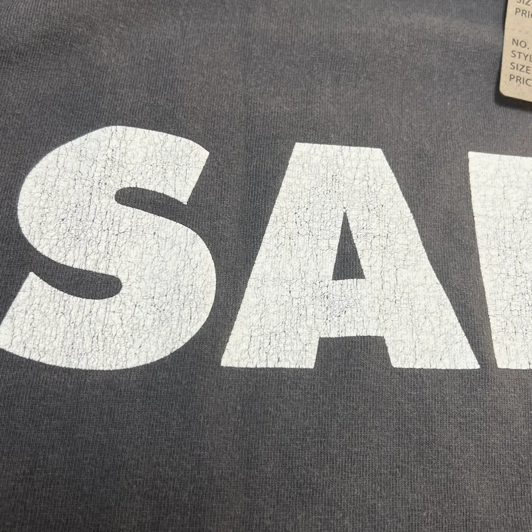 SAINT Mxxxxxx S>N>T LS TEE/BLACK Autumn and winter new style S>N>T slogan crack printed long TEE, washed black S-XL Asut ready-made garments dyed, the whole piece sprayed with horse-hair spray, and then sprayed again to fade the color. The collar and cuffs are frayed. Many hangings are worn NEW VINTAGE. Heavy craftsmanship.